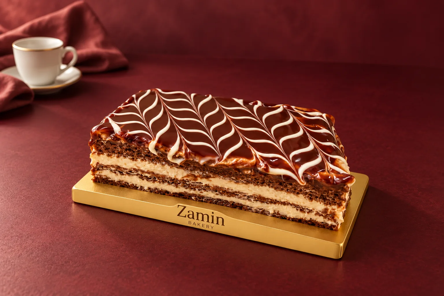Dark feathered cake portion on a Zamin Bakery gold board